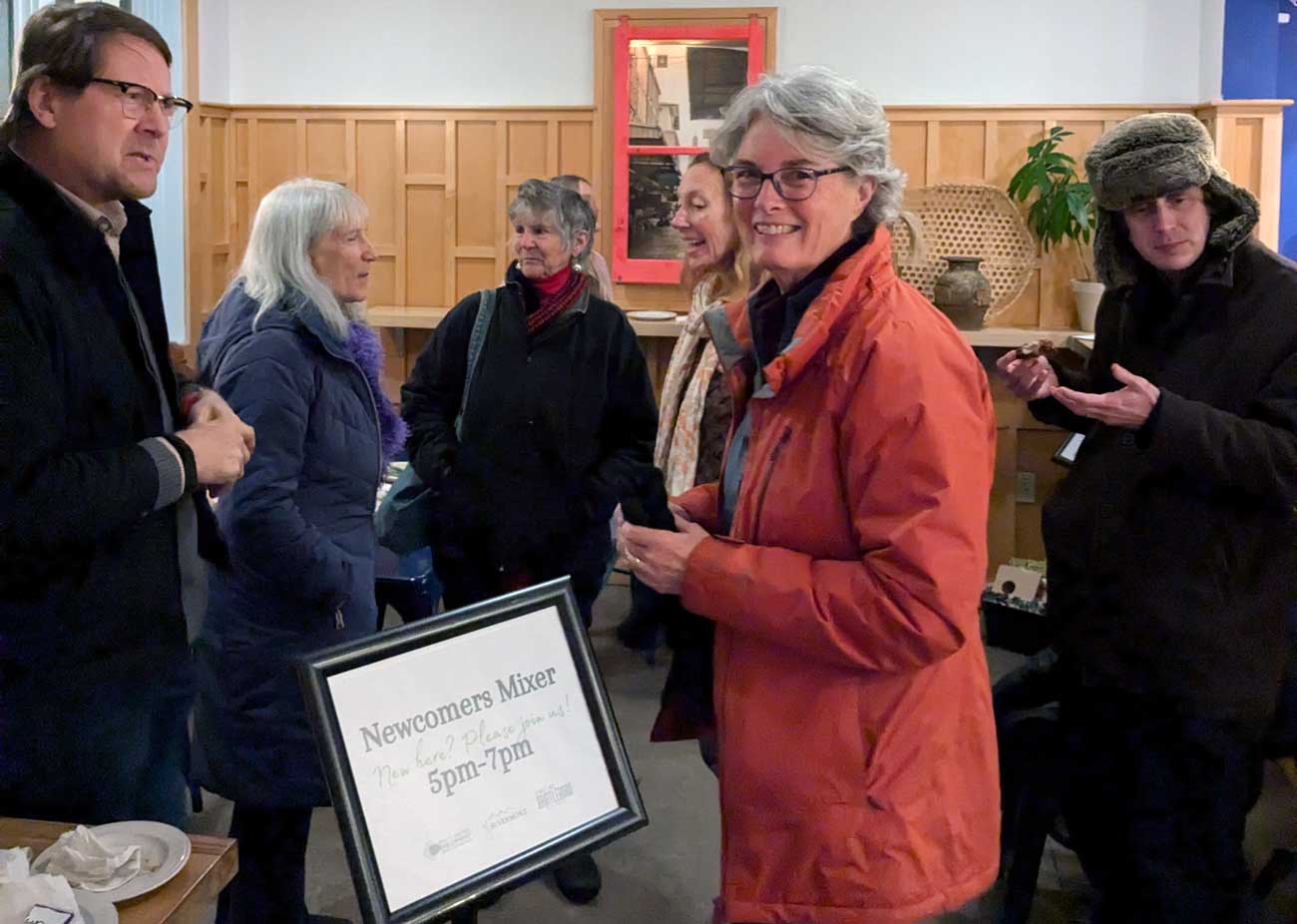 A small group of people at a mixer event wearing winter coats.|